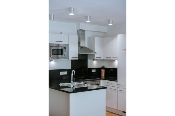 A modern kitchen with white cabinets and a black countertop. It is equipped with a stove, a sink, and modern appliances. - Appartement Bergbach Sölden - Sölden