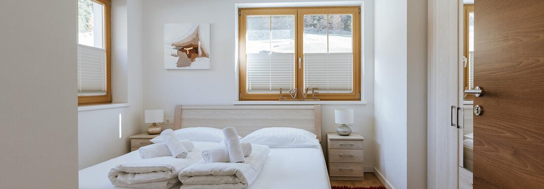 A modern bedroom with a double bed. Large windows provide plenty of daylight and a cozy atmosphere. - Appartement Bergbach Sölden - Sölden