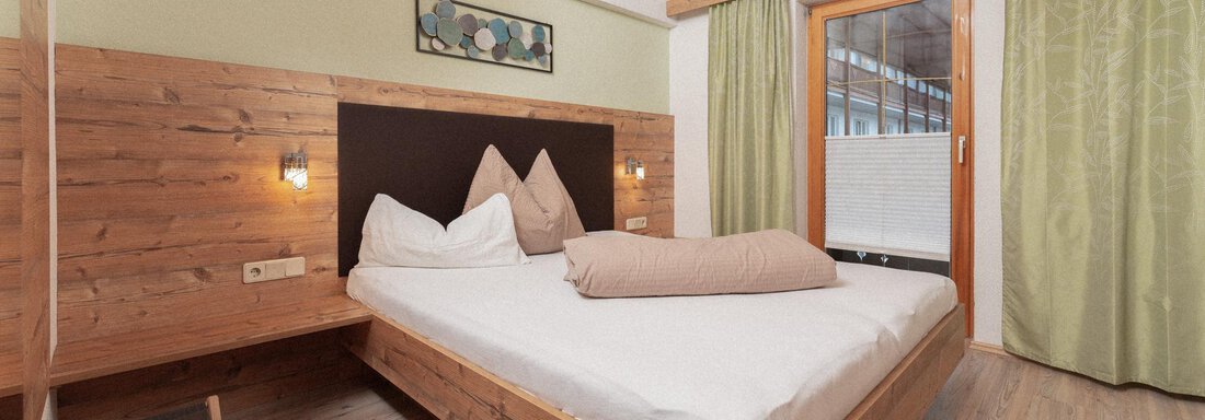Ingemar | © Andreas Ebermann, Appt. Gehörde - Sölden (CC C) A cozy bedroom with a large bed and wooden details. Soft colors and a window with a view of the outdoors create an inviting atmosphere. - Appartement Gehörde Sölden - Sölden