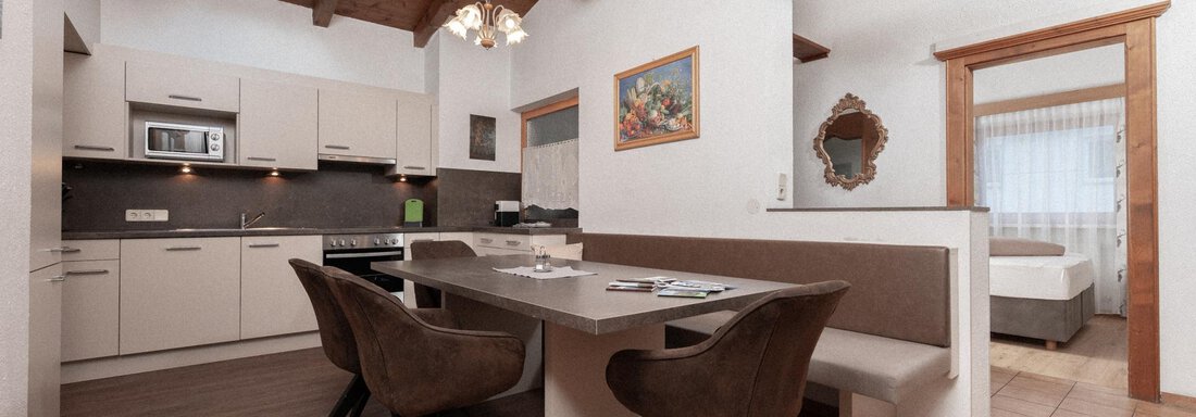 A modern kitchen with wooden ceilings and a large dining table. The room is bright and inviting, perfect for social hours. - Appartement Gehörde Sölden - Sölden