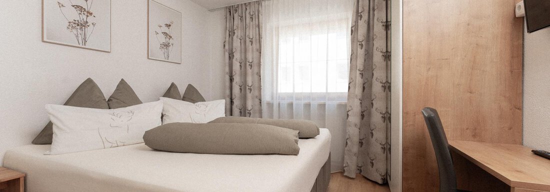 A modern bedroom with a double bed and cozy furnishings. This includes a table, a chair, and decorative pictures on the wall. - Appartement Gehörde Sölden - Sölden