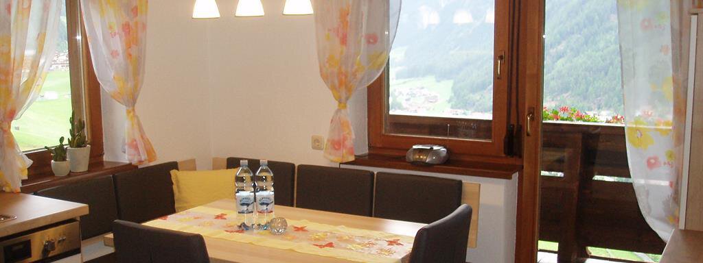Küche mit Sitzgruppe A cozy kitchen with a dining table and chairs. Through the windows, there is a view of the surrounding nature. - Appartement Harmonie - Sölden