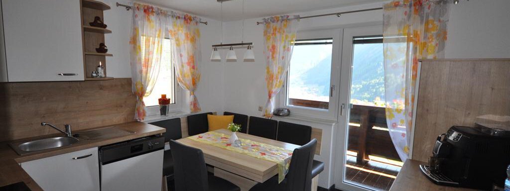 A modern kitchen with a dining area and large windows. The light curtains create a friendly atmosphere and plenty of daylight. - Appartement Harmonie - Sölden
