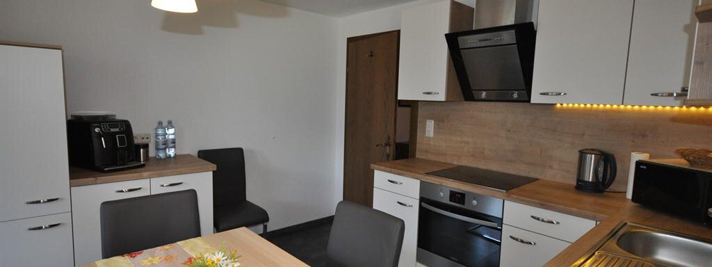 A modern kitchen with wooden shelves and a dining group. The kitchen is bright and friendly, equipped with modern appliances and ample storage space. - Appartement Harmonie - Sölden