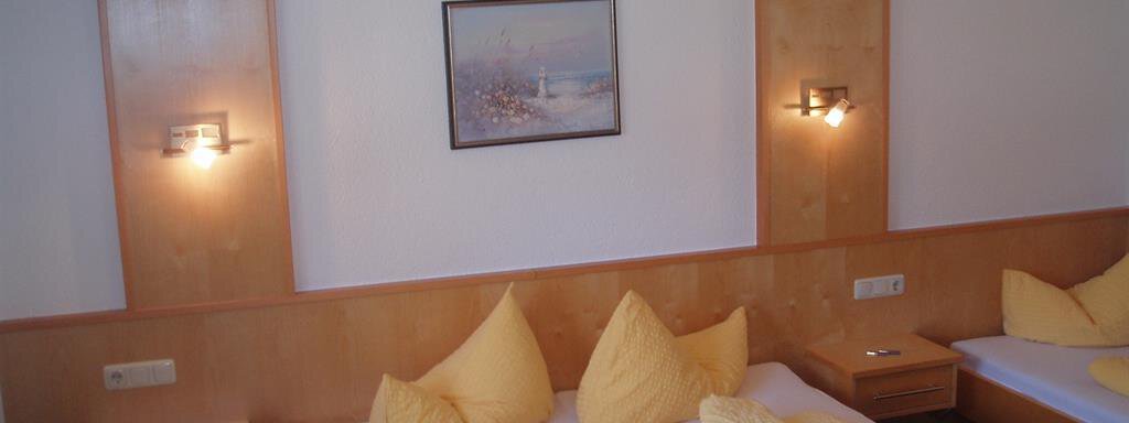 A cozy bedroom with two beds and yellow pillows. The walls are made of wood, and there is a picture hanging over the beds. - Appartement Harmonie - Sölden