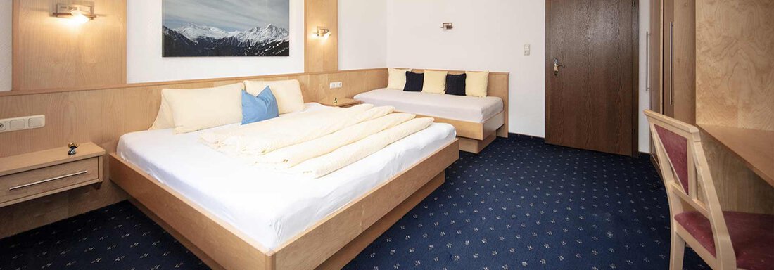 A cozy hotel room with two beds and a beautiful carpet. On the wall hangs a picture of mountain landscapes. - Appartement Harmonie - Sölden