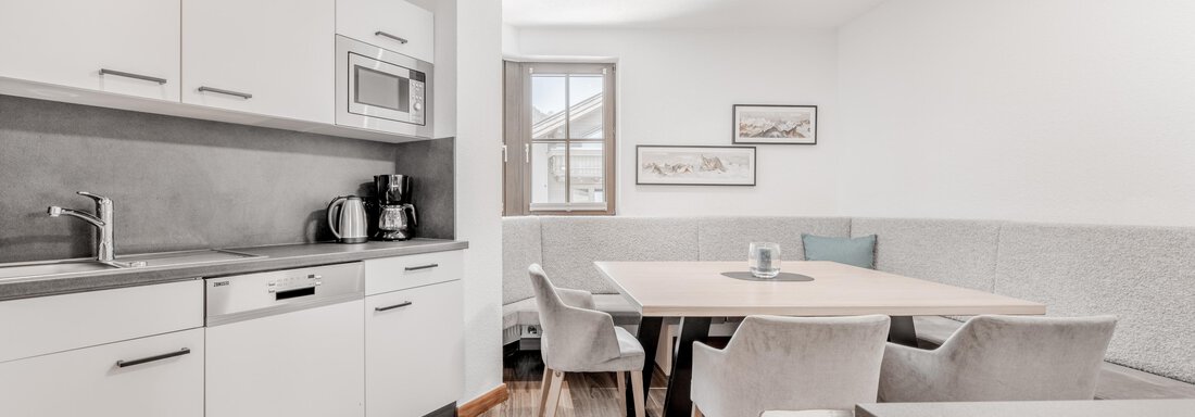Modern kitchen with a large dining table and light furniture. A window provides plenty of daylight. - Appartement Montanara - Sölden
