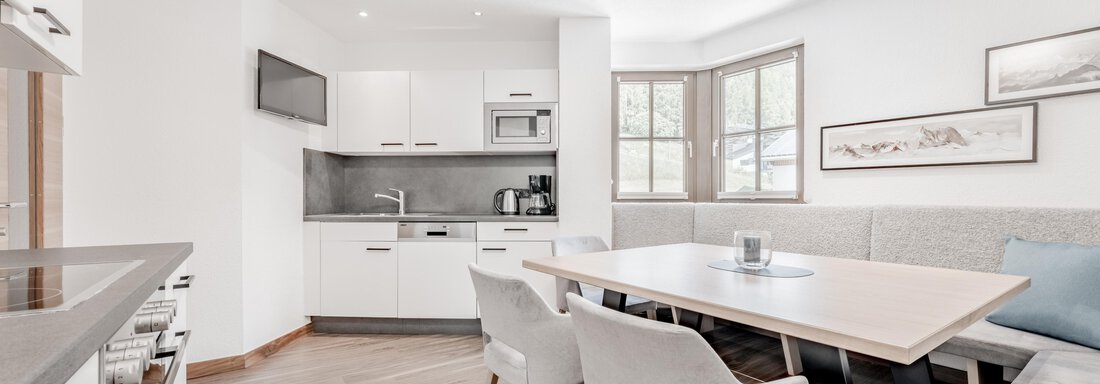 A modern kitchen with a dining area and large windows. The room is bright and warmly designed. - Appartement Montanara - Sölden
