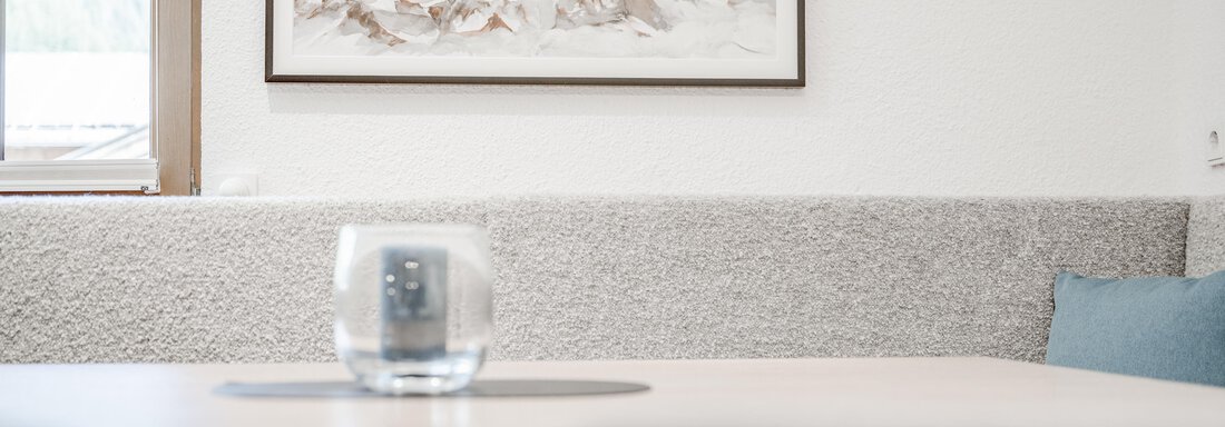 A modern living room with a table and a glass. 

On the wall hang works of art, and the room has a bright, inviting atmosphere. - Appartement Montanara - Sölden