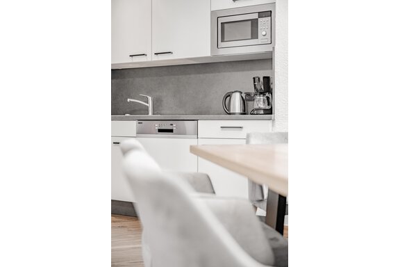 A modern kitchen with white cabinets and modern appliances. The tabletop is made of wood and the chairs are comfortable. - Appartement Montanara - Sölden