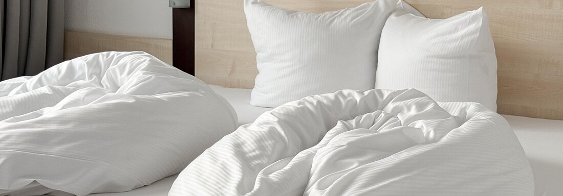 A cozy bed with white pillows and blankets. The background is kept light and simple. - Appartementhaus A CASA "Kristall" - Sölden