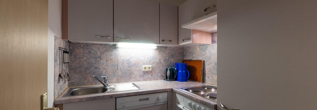 A modern kitchen with bright cabinets and a practical layout. The space is equipped with a sink, a dishwasher, and a stove. - Appartementhaus Karlinger - Sölden