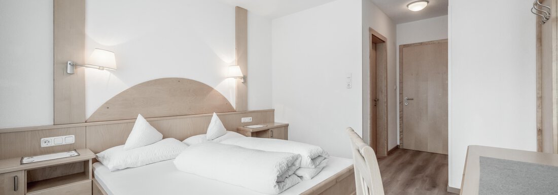 A modern bedroom with a double bed and a simple wood design. The walls are light and the room feels friendly and inviting. - Appartementhaus Kathrin - Sölden