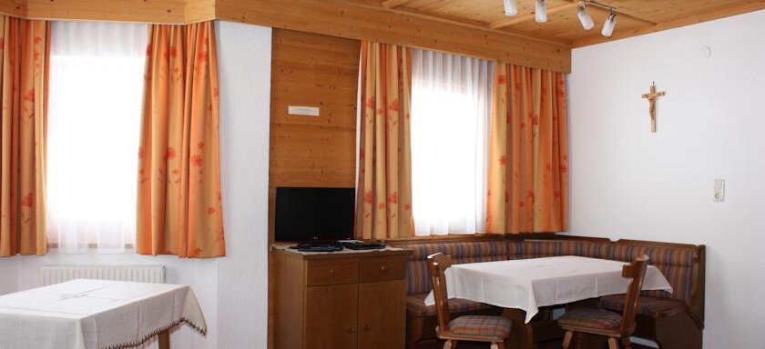 A cozy room with wooden panels, two tables and chairs. Large windows with orange curtains ensure bright light. - Appt. Magda - Sölden