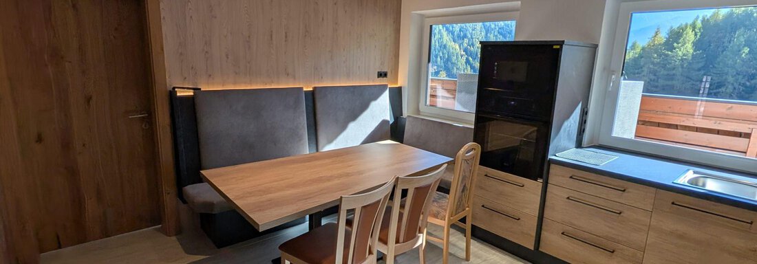 A modern kitchen with a dining table and chairs. Large windows offer a view of the surroundings. - Appt. Rosmarie - Sölden
