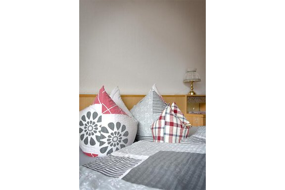 A cozy room with decorative cushions in various patterns. In the background, there is a midnight blue table and a lamp. - Appt. Schnöller - Sölden