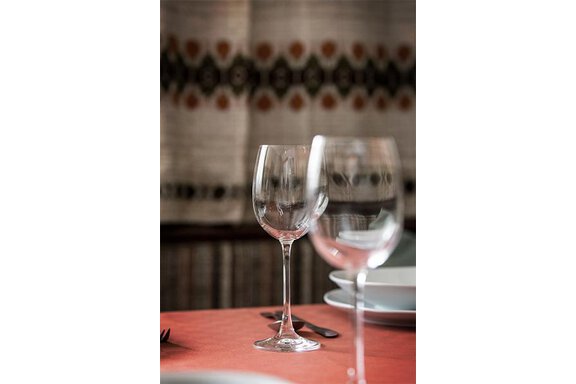 An elegant table with wine glasses and set dishes. The background features a decorative pattern. - Appt. Schnöller - Sölden