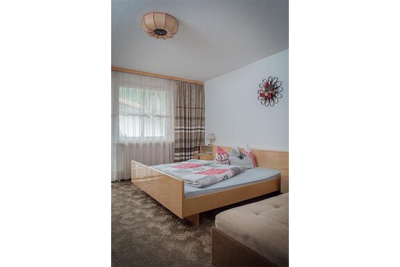 A bright bedroom with a double bed and a cozy seating area. Large windows provide plenty of daylight and an inviting atmosphere. - Appt. Schnöller - Sölden