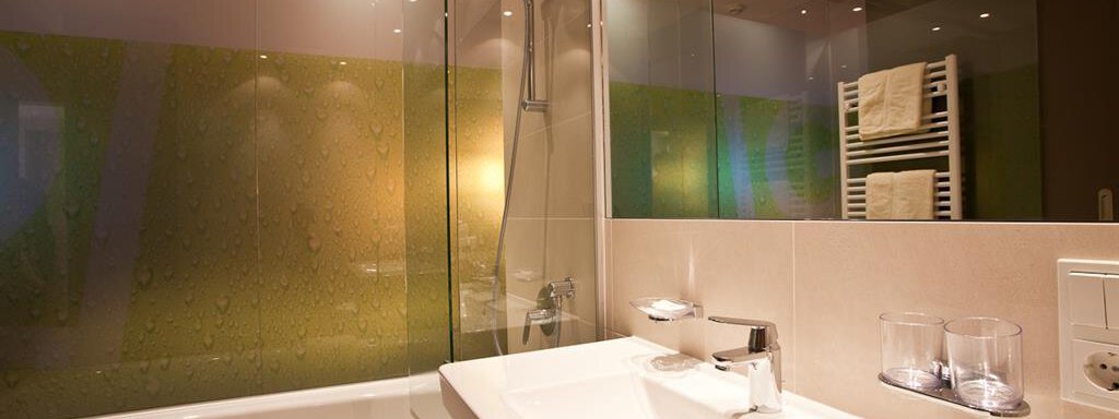 Ein modernes Badezimmer mit einer Duschkabine und einer Badewanne. Die Wände sind hell gefliest und es gibt einen Handtuchhalter mit frischen Handtüchern. - Bäckelar Wirt - Sölden