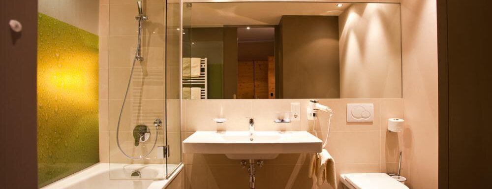 Ein modernes Badezimmer mit einer Badewanne und einer separaten Dusche. Die Wände sind in neutralen Farben gehalten und es gibt ein großes Spiegel. - Bäckelar Wirt - Sölden
