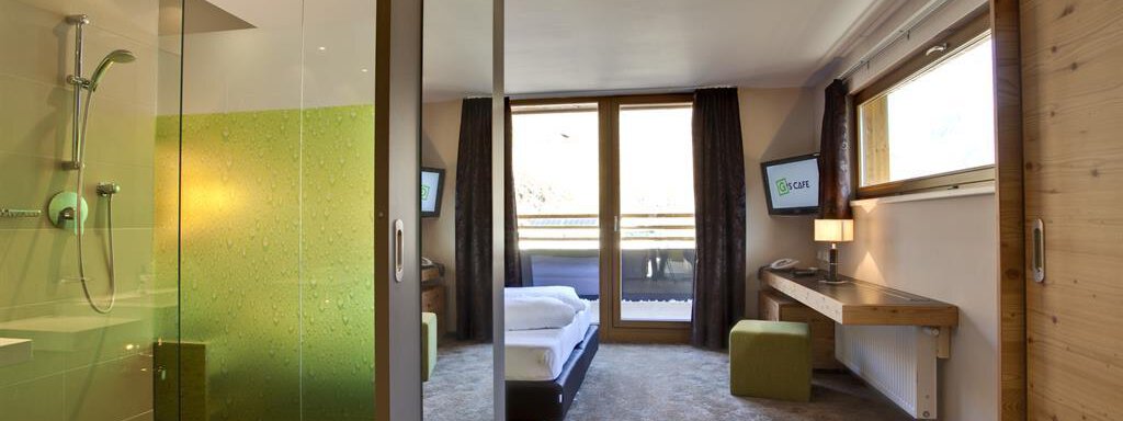Ein modernes Hotelzimmer mit einer Dusche aus Glas und einem großen Fenster. Die Atmosphäre ist hell und einladend mit einem schlichten Design. - Bäckelar Wirt - Sölden