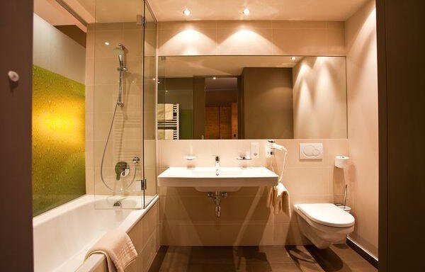 Ein modernes Badezimmer mit einer Dusche und Badewanne. Helle Wände und stilvolle Beleuchtung schaffen eine einladende Atmosphäre. - Bäckelar Wirt - Sölden