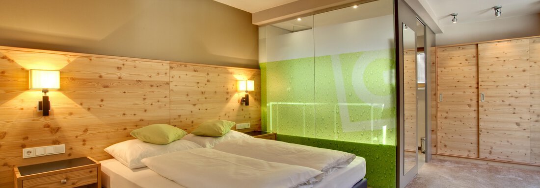 Ein modernes Schlafzimmer mit einem Doppelbett und Holzverkleidung. Der Raum hat große Fenster und eine elegante Gestaltung. - Bäckelar Wirt - Sölden