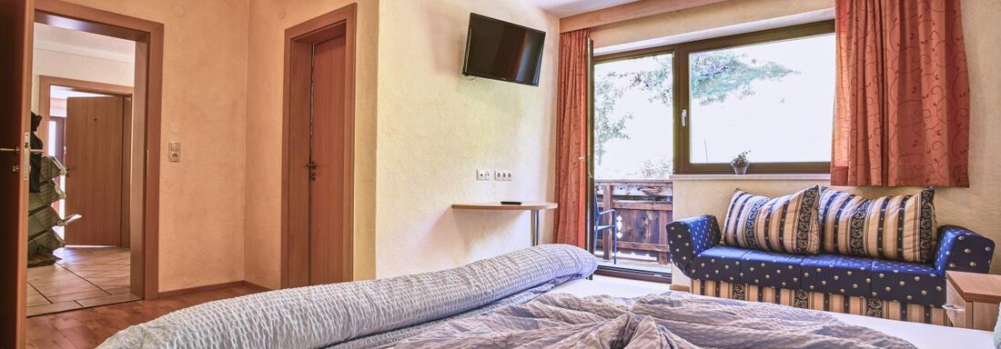 A cozy bedroom with a large bed and a sofa. The room has windows that let in plenty of light and offer a view outside. - Belledonne Ski in & out Appartements - Sölden