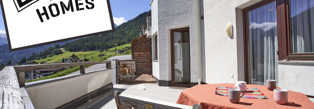 A sunny terrace with a view of the mountains. A table with an orange tablecloth and cups is set up. - Belledonne Ski in & out Appartements - Sölden