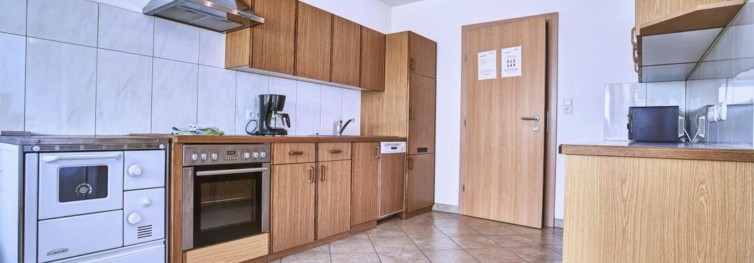 A modern kitchen with wooden cabinets and bright tiles. There is an oven, a sink, and a refrigerator. - Belledonne Ski in & out Appartements - Sölden