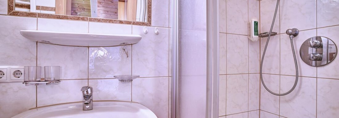 A modern bathroom with a shower, a sink, and bright tiles. The bathroom looks clean and well-lit. - Belledonne Ski in & out Appartements - Sölden