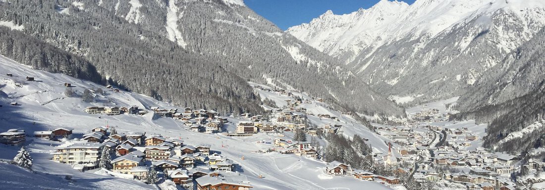 A picturesque mountain landscape with snow-covered hills and a clear sky. In the valley, there are several charming, snow-covered houses. - Belledonne Ski in & out Appartements - Sölden
