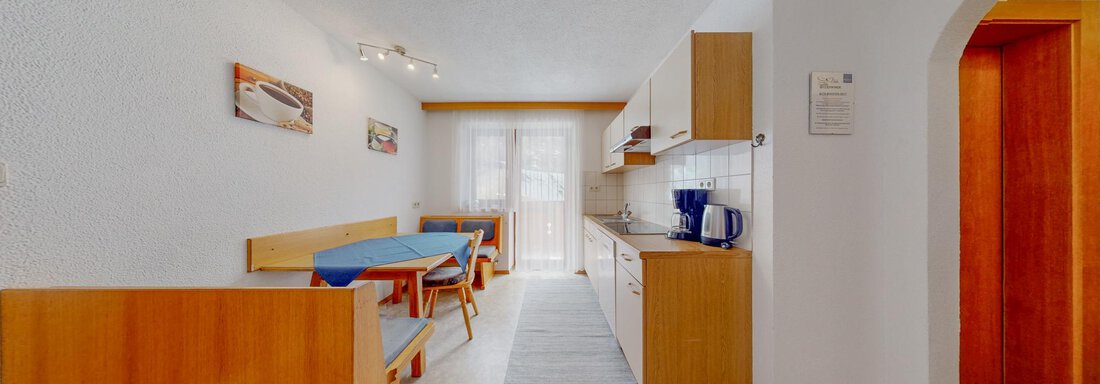 A bright and modern kitchen with a dining table and chairs. Large windows let in a lot of light. - Belmonte Sölden - Sölden