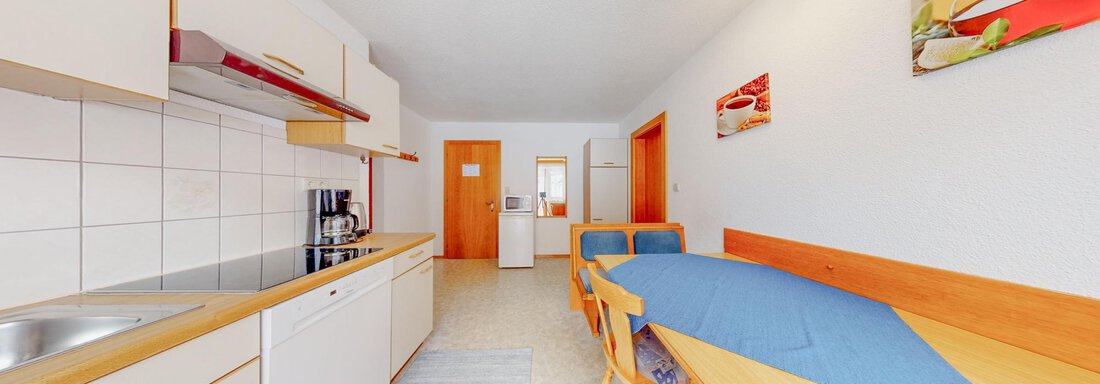 A modern kitchen unit with bright furniture and a dining area. The walls are plain and decorated with colorful pictures. - Belmonte Sölden - Sölden