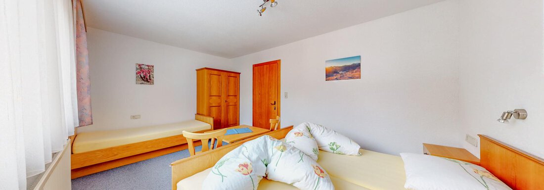 A bright and spacious bedroom with two beds and a small table. The walls are painted in soft colors and there are large windows that let in plenty of daylight. - Belmonte Sölden - Sölden