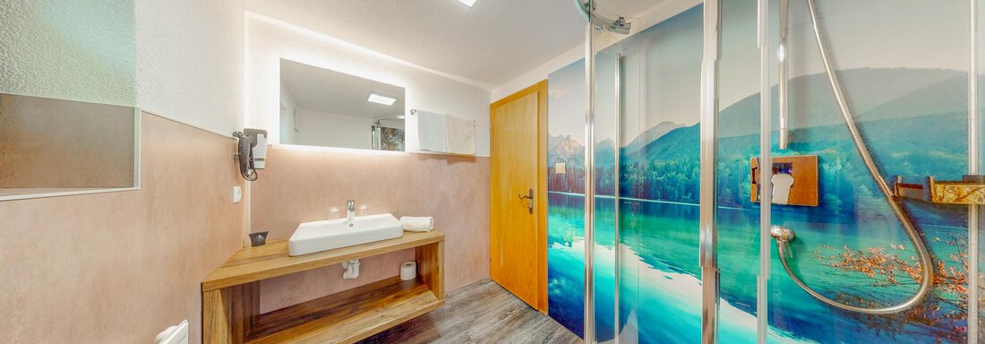 A modern bathroom with a large shower and a wooden vanity. A colorful wall design featuring a landscape motif creates a relaxing atmosphere. - Belmonte Sölden - Sölden
