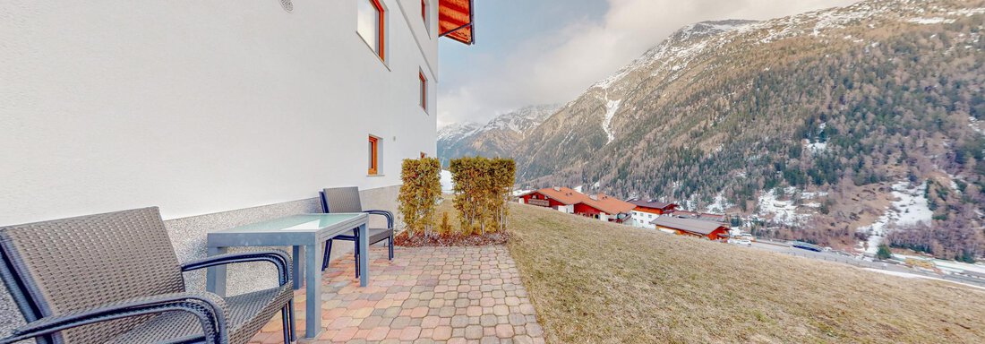 A cozy outdoor area with patio furniture and a view of the mountains. The surroundings are characterized by nature and peaceful landscapes. - Belmonte Sölden - Sölden