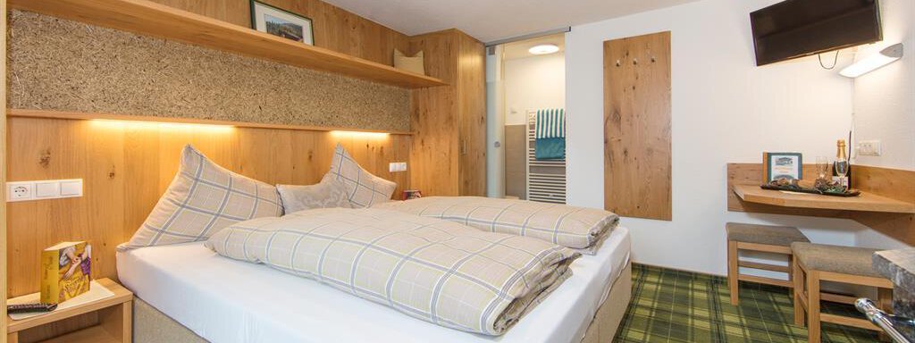 A cozy hotel room with two single beds and wooden shelves. The room has a friendly atmosphere and modern amenities. - Brandlehof - Sölden