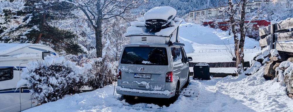Stellplatz Panorama Winter Ein Auto steht im Schnee, umgeben von einer winterlichen Landschaft. Im Hintergrund sind schneebedeckte Berge und ein klarer Himmel zu sehen. - Camping Sölden - Sölden