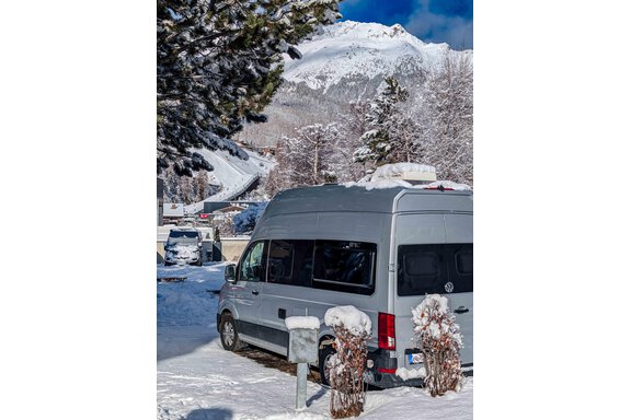Ein Wohnmobil steht auf einem schneebedeckten Parkplatz mit Bergen im Hintergrund. Die Umgebung ist winterlich und malerisch. - Camping Sölden - Sölden
