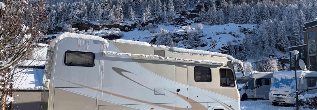 Ein Wohnmobil steht in einer schneebedeckten Landschaft. Im Hintergrund sind verschneite Berge und Bäume zu sehen. - Camping Sölden - Sölden