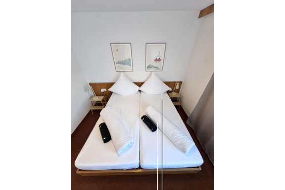 A simple bedroom with two single beds and white bedcovers. Two pictures hang on the wall, and there are small nightstands. - CASA bianco DUE - Sölden