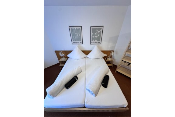 A modern bedroom with two single beds and minimalist decor. The walls are adorned with contemporary artworks. - CASA bianco DUE - Sölden