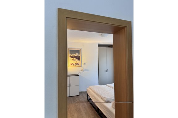 A view of a bedroom with two beds and a desk. A poster with the inscription "Sölden" is hanging on the wall. - CASA bianco DUE - Sölden