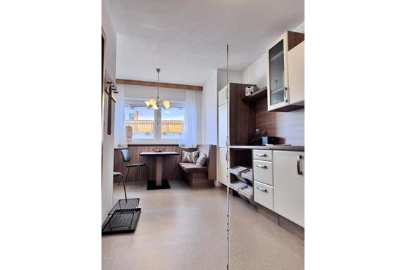 A modern kitchen with a dining area and plenty of natural light. The furniture is designed to be bright and cheerful. - CASA bianco DUE - Sölden
