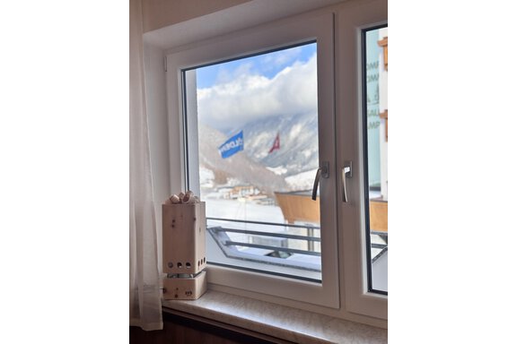 A window overlooking snow-covered mountains and waving flags. On the windowsill, there is a wooden container with eggs. - CASA bianco DUE - Sölden