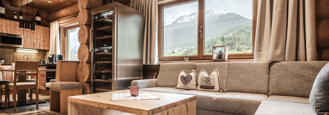 1617_Chalet_Soelden_24_205 A cozy living area in a log cabin with a view of the mountains. The decor is modern and warm, featuring a large window and an inviting couch. - Chalet Resort Sölden - Sölden
