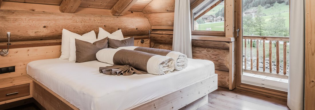 A cozy bedroom in a wooden house with a large window and a view of nature. The decor is modern and inviting, perfect for relaxation. - Chalet Resort Sölden - Sölden