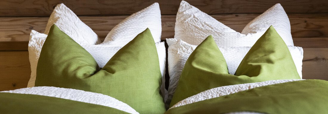 Two beds with green and white pillows. The pillows are neatly arranged and create an inviting atmosphere. - Chalet Resort Sölden - Sölden