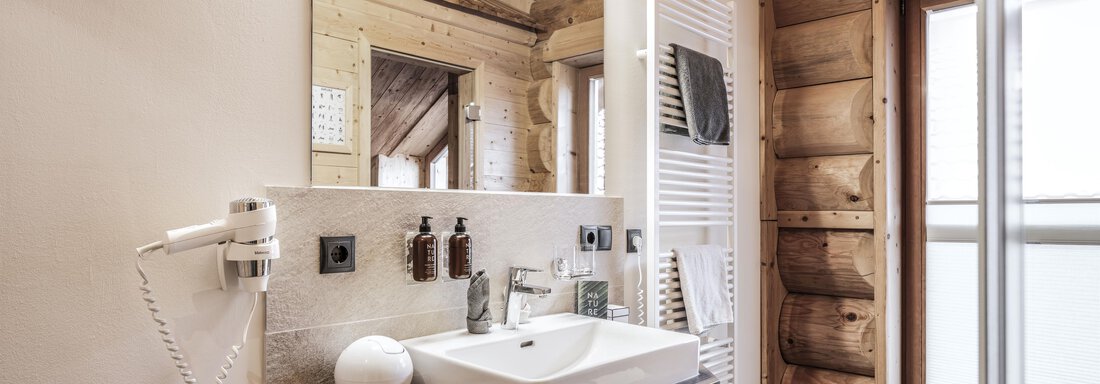 A modern bathroom with a stylish sink and a large mirror. The walls are made of wood, creating a cozy atmosphere. - Chalet Resort Sölden - Sölden